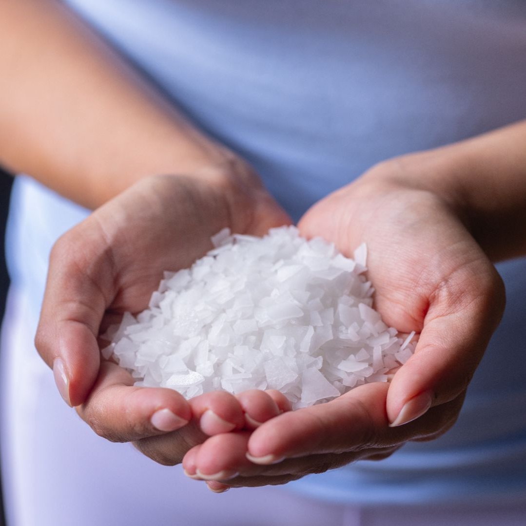 Female in a purple shirt holding magnesium flakes in both hands 